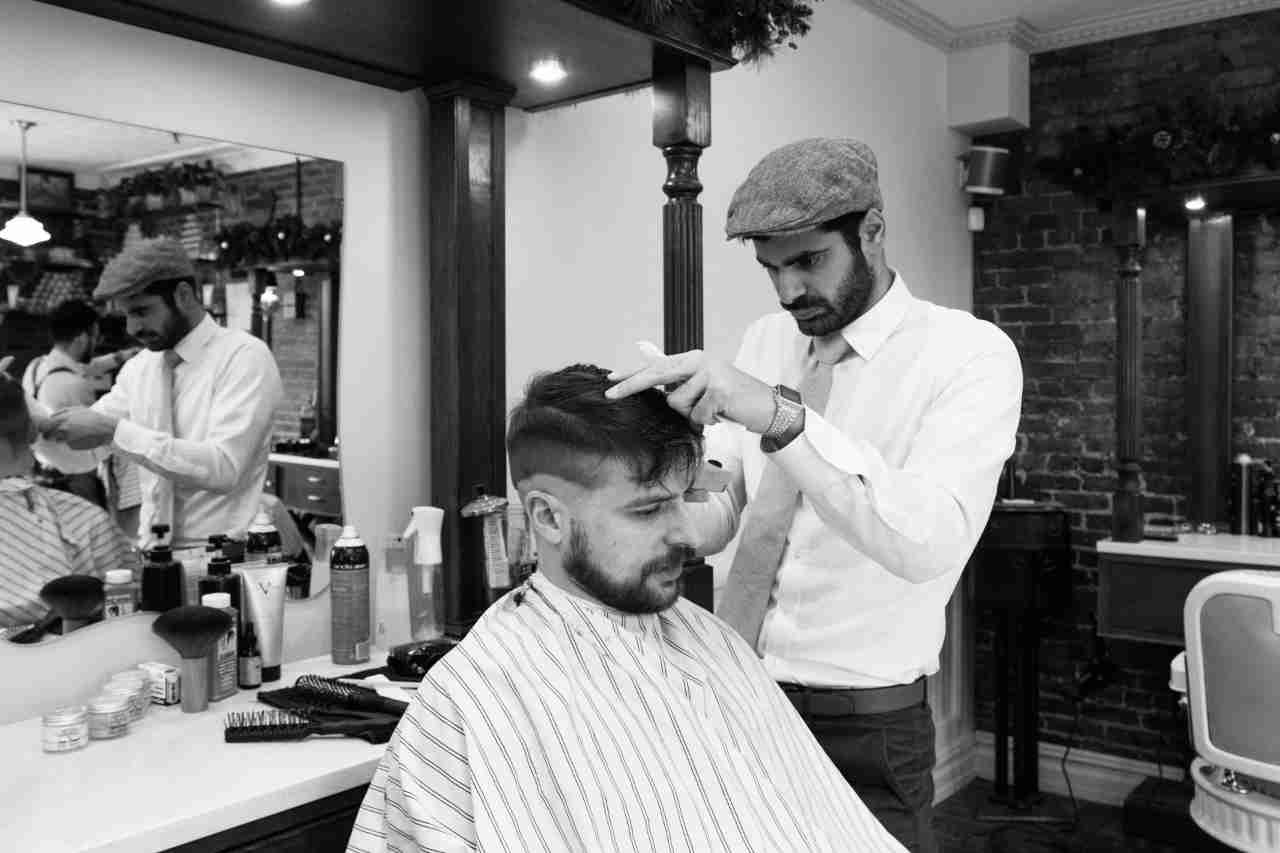 male hair stylist cutting hair of a male customer