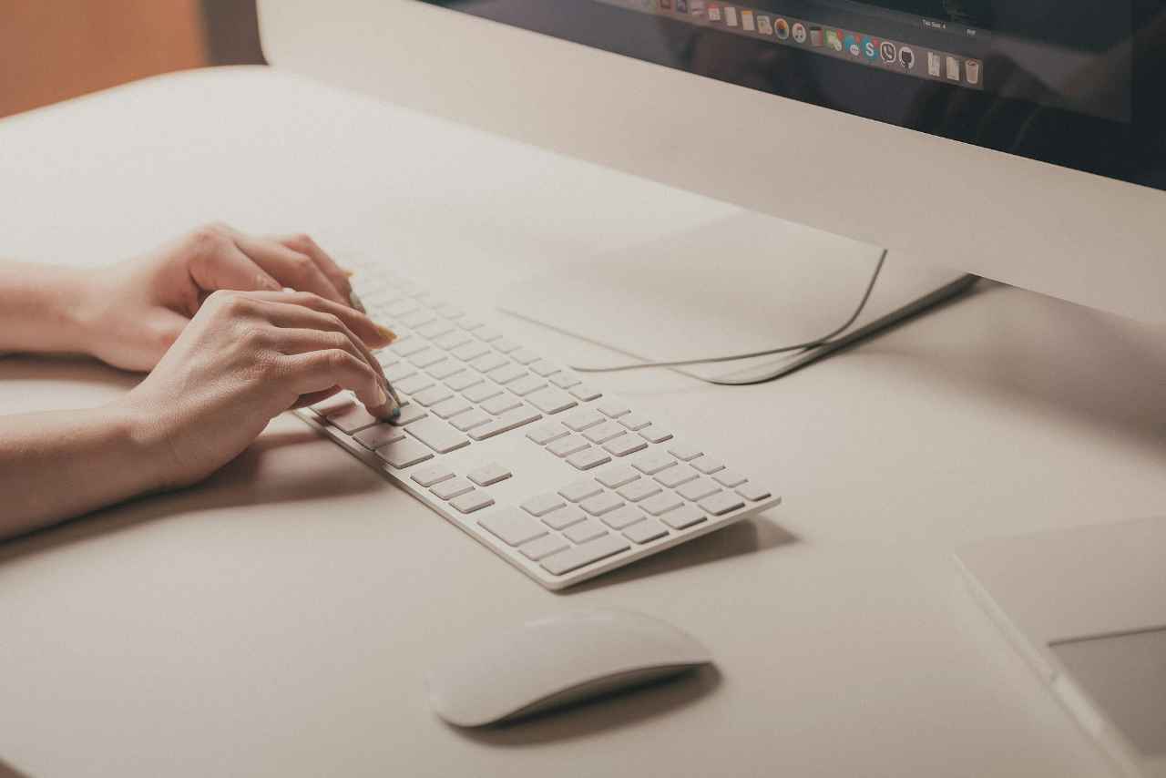 woman typing on a keyboard in front of Mac computer