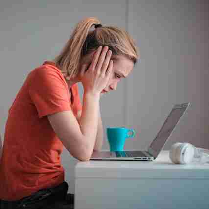 young woman looking troubled in front of a laptop