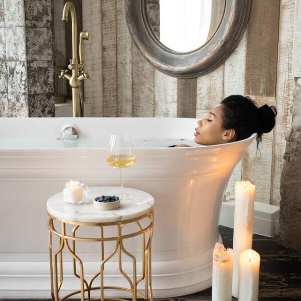 woman taking an aroma bath with white wine on a side table