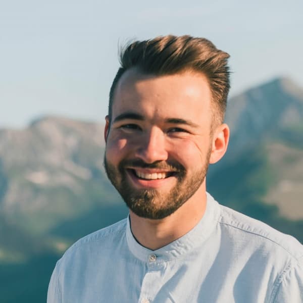 Man smiling in front of a mountain