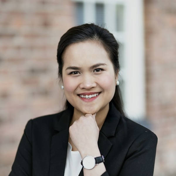 Woman smiling in front of a brick building with a watch on her left wrist