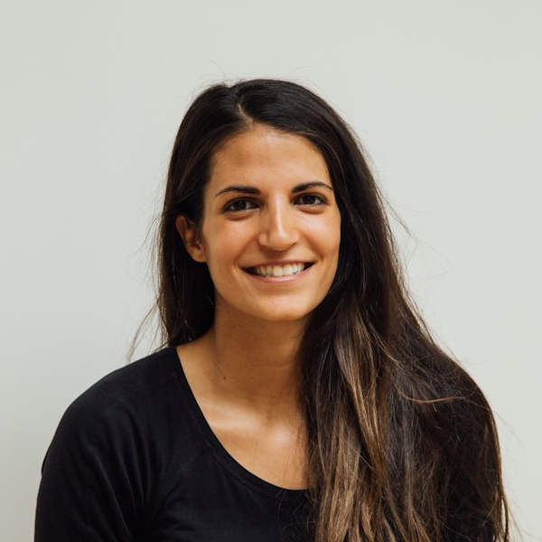 Woman smiling in front of an off-white wall